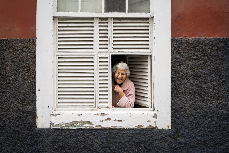 Señora asomándose por una ventana blanca de madera